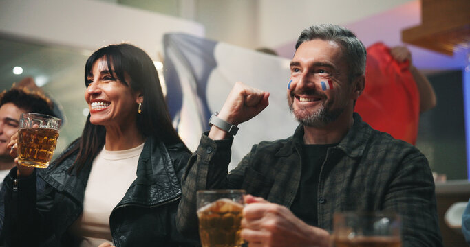 Man, beer and watching tv with celebration at sports bar, football or competition with France flag. Mature people, group and fist pump with soccer game, live stream or broadcast with drinks at pub