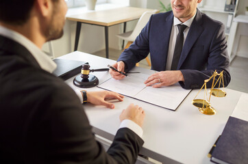 Client engaging in a conversation with a lawyer or attorney, discussing a contract or case during a meeting in the office. Law, paperwork, and the importance of legal consultation.