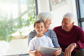 Grandparents, boy and tablet in home, smile and bonding in portrait with game, elearning or puzzle. Senior man, woman and child with tech, application and scroll with problem solving at family house