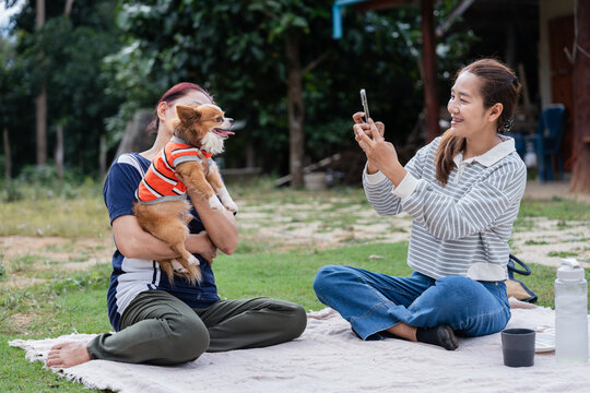 Happy Asian daughter taking photo of senior mother with dog symbolizing appreciation and creating memories
