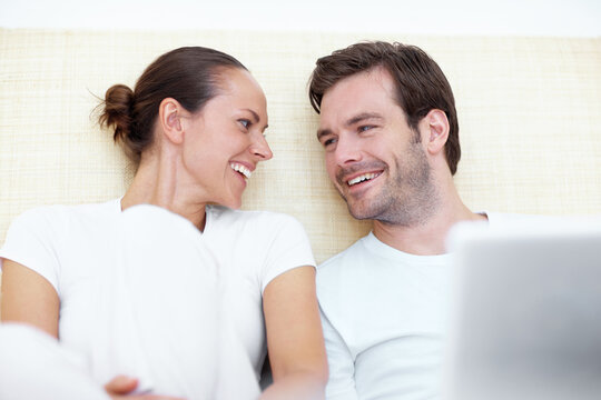 Happy, laptop and couple in bed in morning for online shopping, internet and website in home. Marriage, relax and man with woman on computer for research, connection and bonding in bedroom together