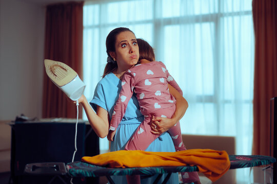 Overworked Mom Irons Laundry While Holding Daughter. Single mother taking care of her kid while doing her chores
