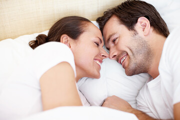 Wakeup, happy and above of couple in bed for resting, comfortable and bonding in morning. Love, bedroom and man with woman together for connection, healthy relationship and relax on weekend in home