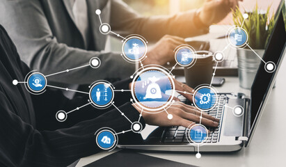 Professionals engage in collaborative work on laptops with graphic icons, symbolizing digital communication and teamwork in a stylish office environment. Tessel