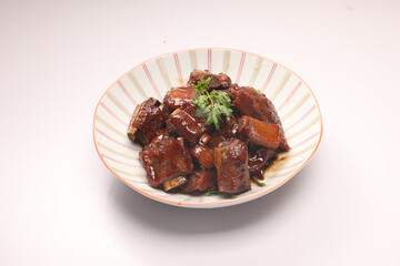 Top view of sweet and sour pork ribs on striped plate isolated