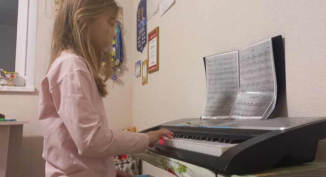 Young girl playing synthesizer and practicing music indoors at home   - Powered by Adobe
