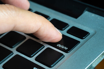 Finger of the computer user, he presses the delete button on the computer keyboard	