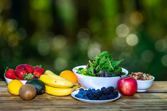 Breakfast served on wooden table. Fresh muesli with yogurt, fruit, and berries. Granola with milk and honey. Oatmeal with juicy berries. Healthy eating concept with organic food and fiber on green. - Powered by Adobe
