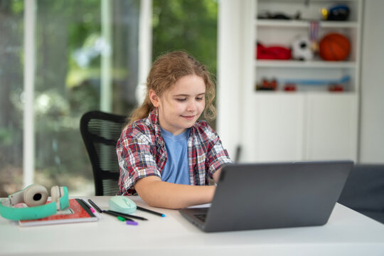 Child learning at home with laptop and books. Kid studying in a cozy home classroom. Kid with homework. Online lessons. Education concept. Child tutoring at home. Boy doing schoolwork in kids room.
