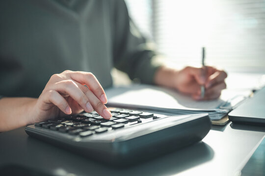 analysis, accounting, finance, budget, tax, calculation, report, investment, profit, audit, Hands using a calculator and writing on documents represent financial analysis and accounting work.