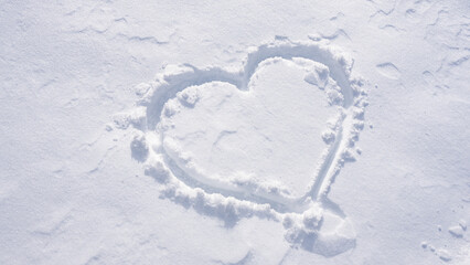 Snow heart on a white winter background. Frosty heart shape in snowy field. Romantic snow heart drawing outdoors. Winter love symbol on frozen surface. Snowflake heart detail. Snow love.
