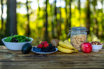 Breakfast served on wooden table. Fresh muesli with yogurt, fruit, and berries. Granola with milk...