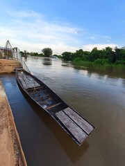 Old Wooden Boat Docked at Riverside with Calm Waters and Greenery