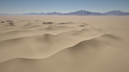 Golden sand dunes stretch endlessly under a bright blue sky. The gentle curves of the dunes contrast with distant mountain peaks, creating a tranquil and serene atmosphere.