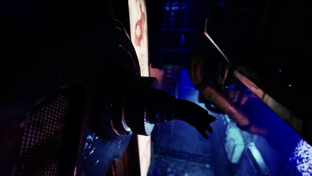 In a dark industrial area, shadows loom as blue light casts an eerie glow. Pipes and machinery create a haunting atmosphere of mystery and suspense. The air is thick with intrigue and tension. - Powered by Adobe