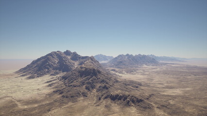 Fototapeta premium Majestic mountains rise dramatically in a vast desert region under a bright blue sky. The arid terrain stretches endlessly, creating an awe inspiring scene of natural beauty.