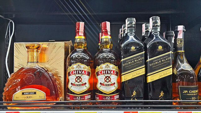 A vibrant display of various whiskey bottles arranged elegantly on a shelf, showcasing a range of premium brands, each with distinct features. Thailand, December 1, 2025
