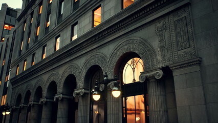 Fototapeta premium A grand historic building features intricate arches and detailed architecture. The warm glow of lights from the windows creates an inviting atmosphere in the early evening.