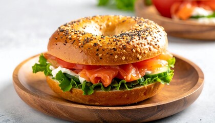A close-up shot of a bagel sandwich filled with salmon, lettuce, tomatoes, and cream cheese, resting on a wooden plate