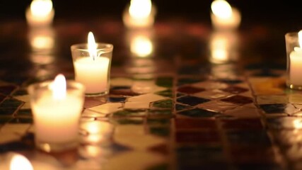 Burning candles illuminate a patterned surface in soft focus night setting