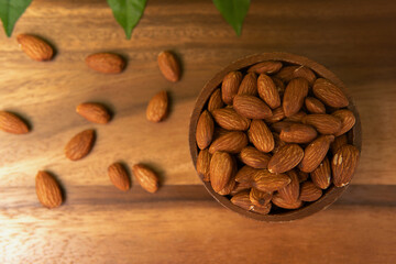 Top view above fresh plant based protein wooden brown bowl of raw uncooked almond on wood tray background perfect for nutritious snacks