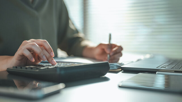 Close-up of hands using a calculator and writing on financial documents, representing budgeting, tax management, cost analysis, and professional accounting processes.