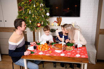 Festive family feast by candlelight on Christmas Day. Mom, dad, and girl and boy sit together, celebrating Christmas surrounded by love, warmth, and joy, sharing dinner and enjoying food.
