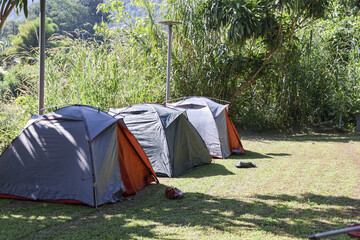 Peaceful camping scene with tents set up on green grass for outdoor adventure. summer vacation in nature at campsite park, perfect travel getaway for relaxation