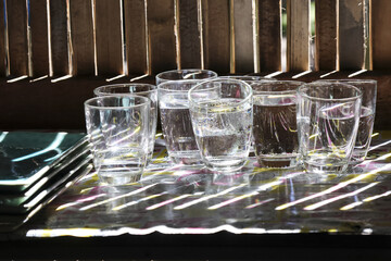 Set of transparent shot glass drinks filled with clear alcohol on serving tray. dramatic pattern of light and shadow creates an intimate mood for party or event at bar