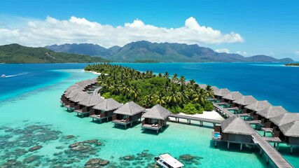 Aerial view of overwater bungalow resort with thatched roof on tropical island with turquoise lagoon and mountain backdrop - Powered by Adobe