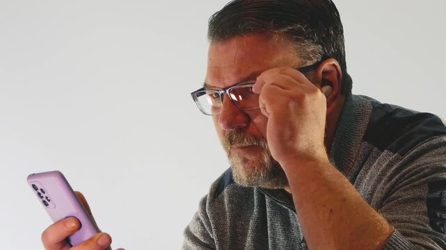 Middle aged man struggles to read small text on smartphone screen in indoor setting