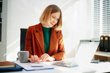 Business woman reviewing documents at desk in modern office. Ideal for finance, marketing, startup workflow, data analysis, productivity, and remote work themes.