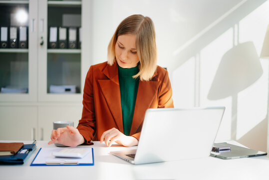 Business woman reviewing documents at desk in modern office. Ideal for finance, marketing, startup workflow, data analysis, productivity, and remote work themes.