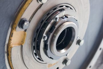 Metallic mechanical assembly featuring a central threaded hub, bearing, and bolted components, highlighting industrial detail and texture.