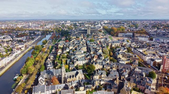 Aerial drone pan over Le Mans cityscape, sweeping across Cath&eacute;drale Saint-Julien and the old town rooftops tracing the meandering Sarthe River through a patchwork of rooftops and tree-lined avenues.