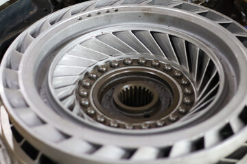 Detailed metallic torque converter stator or impeller assembly with central splined hub and exposed ball bearings, symbolizing complex automotive engineering and precision transmission repair.