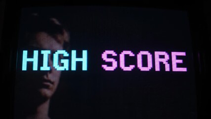Retro gaming screen from the eighties displaying a pixelated high score with a focused player's reflection in the dark background - Powered by Adobe