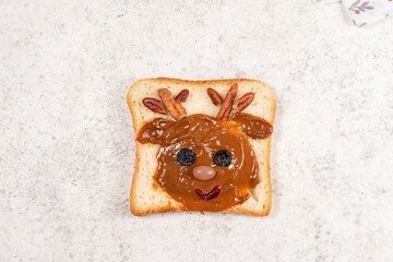 Creative holiday toast with peanut butter and toppings shaped like a reindeer on a festive napkin