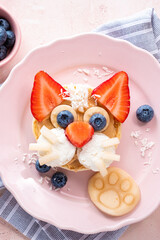 Creative breakfast idea featuring a cat face made from fruit and pancakes on a pink plate
