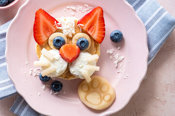 Creative breakfast idea featuring a cat face made from fruit and pancakes on a pink plate