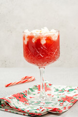 Refreshing holiday drink served in a crystal glass with whipped cream and candy cane on a festive napkin