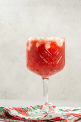 Refreshing holiday drink served in a crystal glass with whipped cream and candy cane on a festive napkin