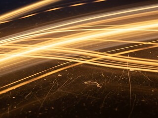 Abstract background with diagonal, fiery orange and yellow light streaks conveying speed and energy against a grunge black texture