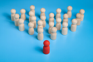 red wooden figure stand to the wooden group crowd. isolated on blue background. leadership and teamwork concept