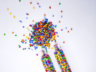 Colorful polymer masterbatch gradation, colorful pigment resin pellets in glass tubes poured on a white background, suitable as a product catalog design for industrial plastic manufacturing companies
