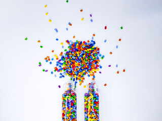 Colorful polymer masterbatch gradation, colorful pigment resin pellets in glass tubes poured on a white background, suitable as a product catalog design for industrial plastic manufacturing companies