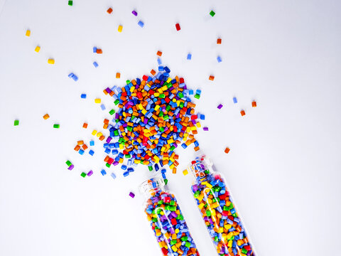 Colorful polymer masterbatch gradation, colorful pigment resin pellets in glass tubes poured on a white background, suitable as a product catalog design for industrial plastic manufacturing companies
