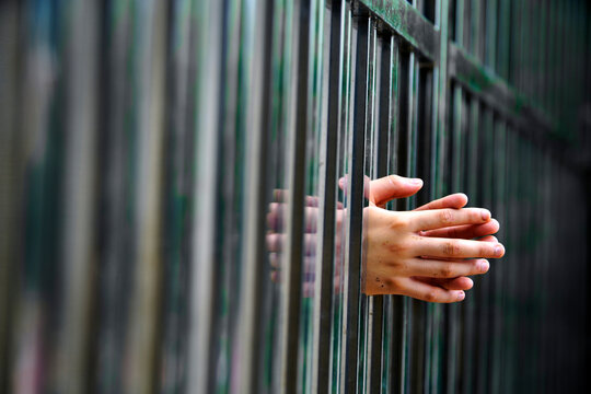 Hands Reaching Through Bars Symbolizing Confinement and Isolation