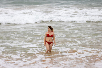 Woman in Red Swimsuit Walking in the Waves on Hikkaduwa Beach, Sri Lanka