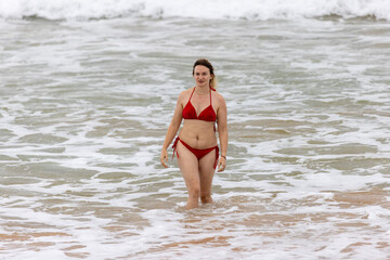 Woman in Red Swimsuit Walking in the Waves on Hikkaduwa Beach, Sri Lanka